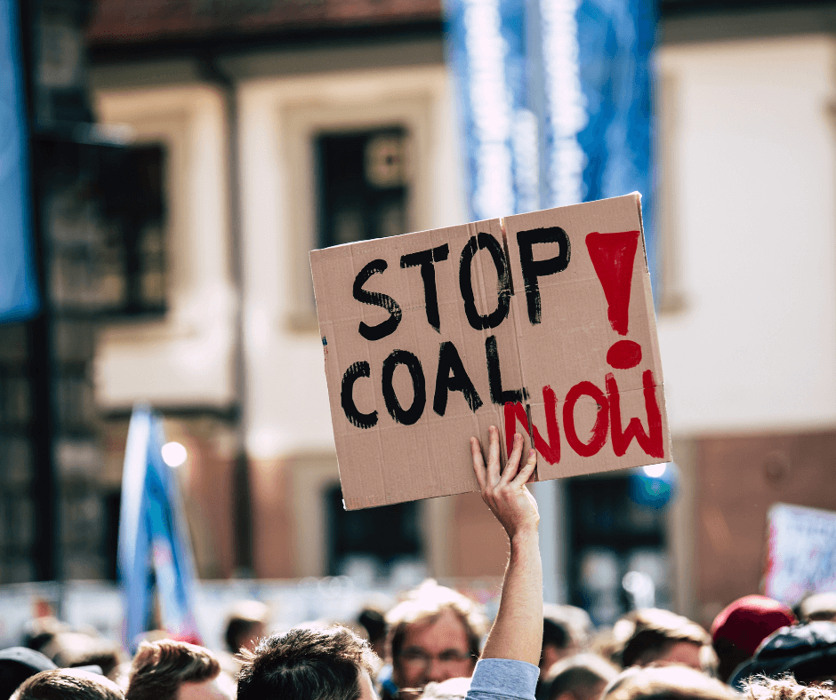 At a climate change march, an attendee holds up a sign that reads, “Stop Coal Now!”