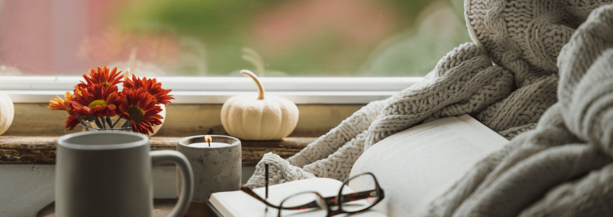 A cozy autumn reading nook by a window; photo via Mundus Images/Canva.